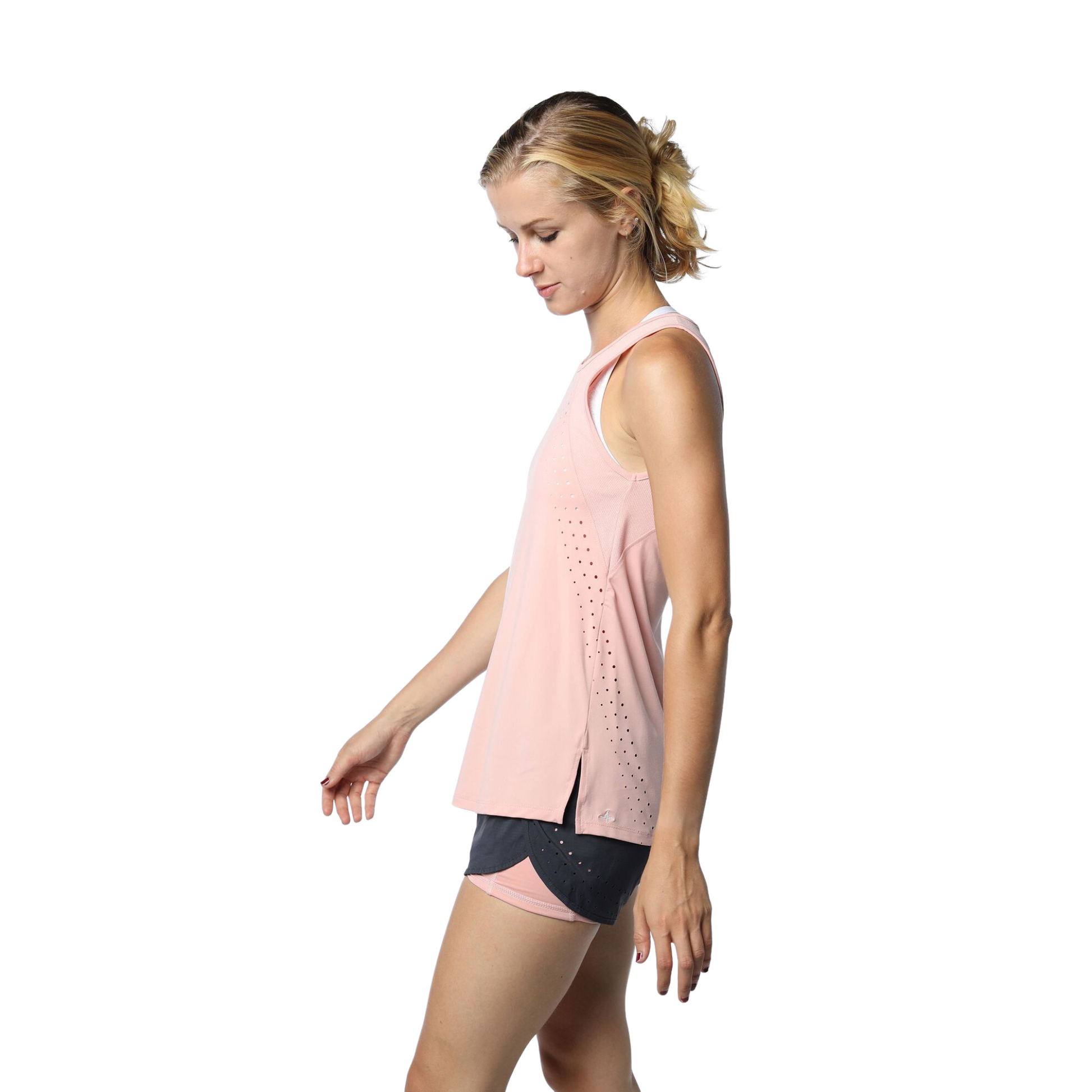 Woman wearing a blush pink tank top and black shorts, with arms at her sides.