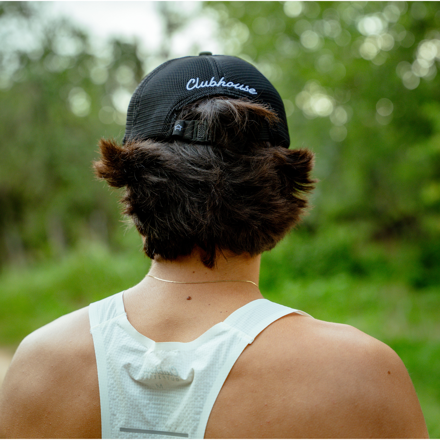 Person wearing a black cap with 'Clubhouse' branding outdoors